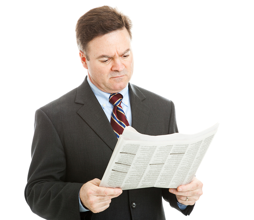 Businessman reading bad news in the newspaper.  Could be financial or political news.  Isolated on white.